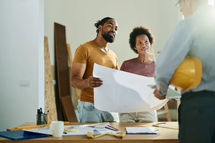 Homeowners reviewing renovation design plans and blueprints with contractor for kitchen and bathroom remodel in Toronto