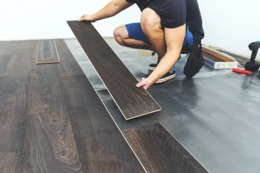 Installer laying new wood-look plank flooring during a bungalow main-floor renovation