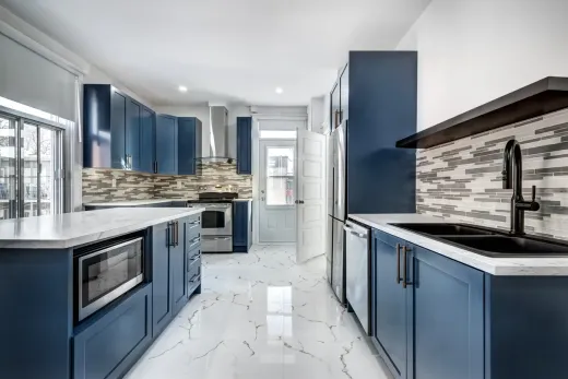 Kitchen with blue cabinets and marble-look stone counters, the kind of upgrade a failed countertop often leads to