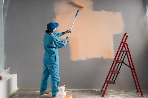 Painter rolling fresh paint onto interior walls, the stage where sheen and formula choices start to matter in wet rooms